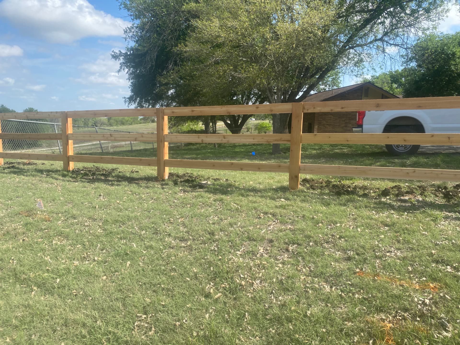 Finished three rail wood fence beside a grassy residential property