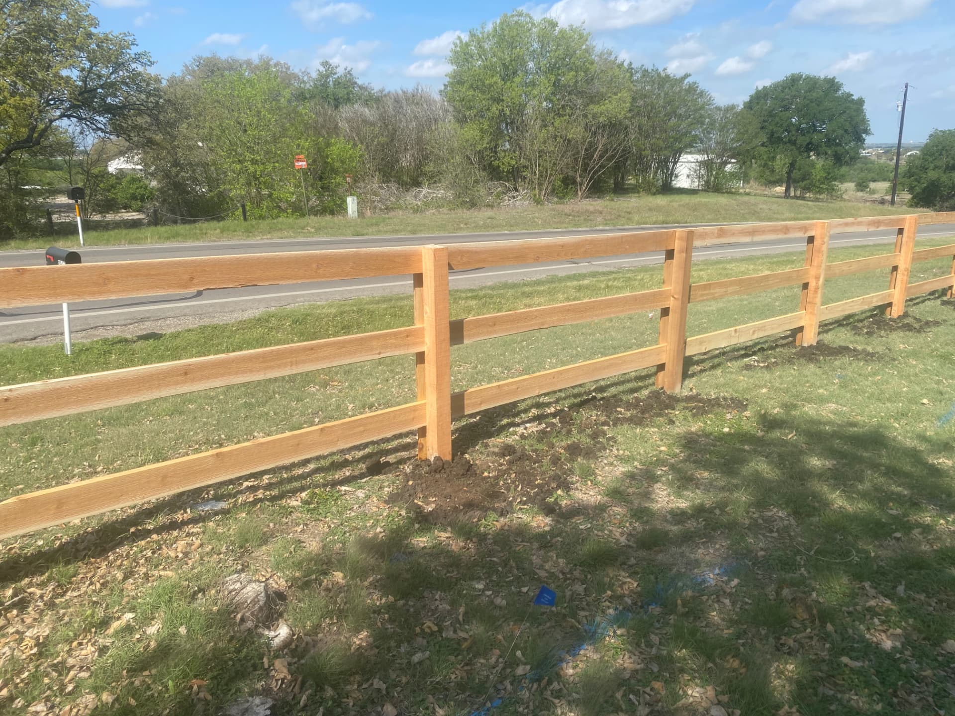 Finished three rail wood fence following a roadside lawn