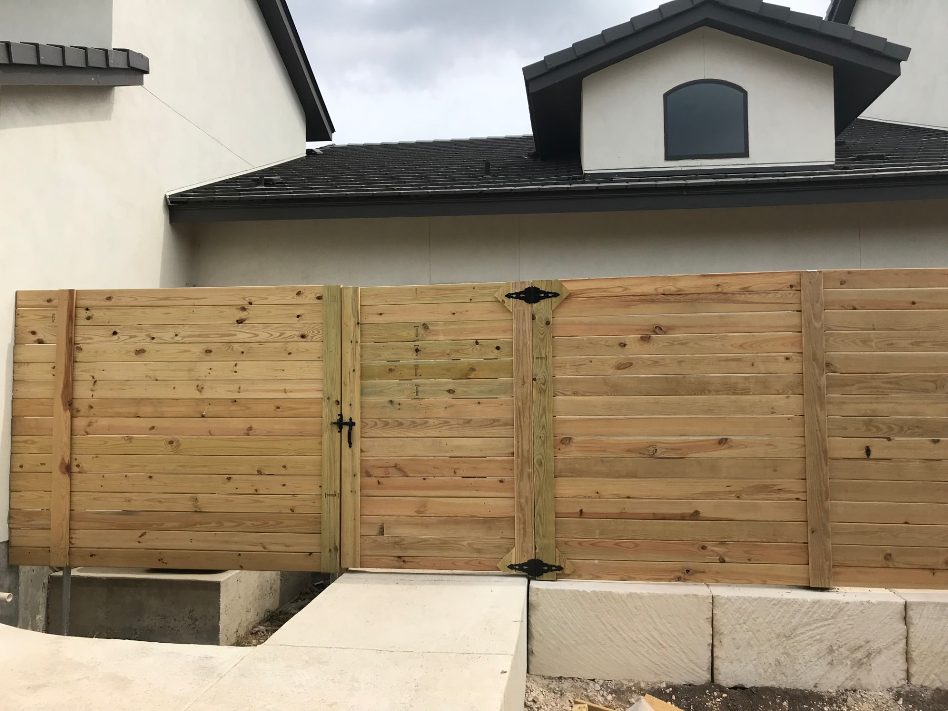Horizontal wood privacy fence and gate installed beside a modern home
